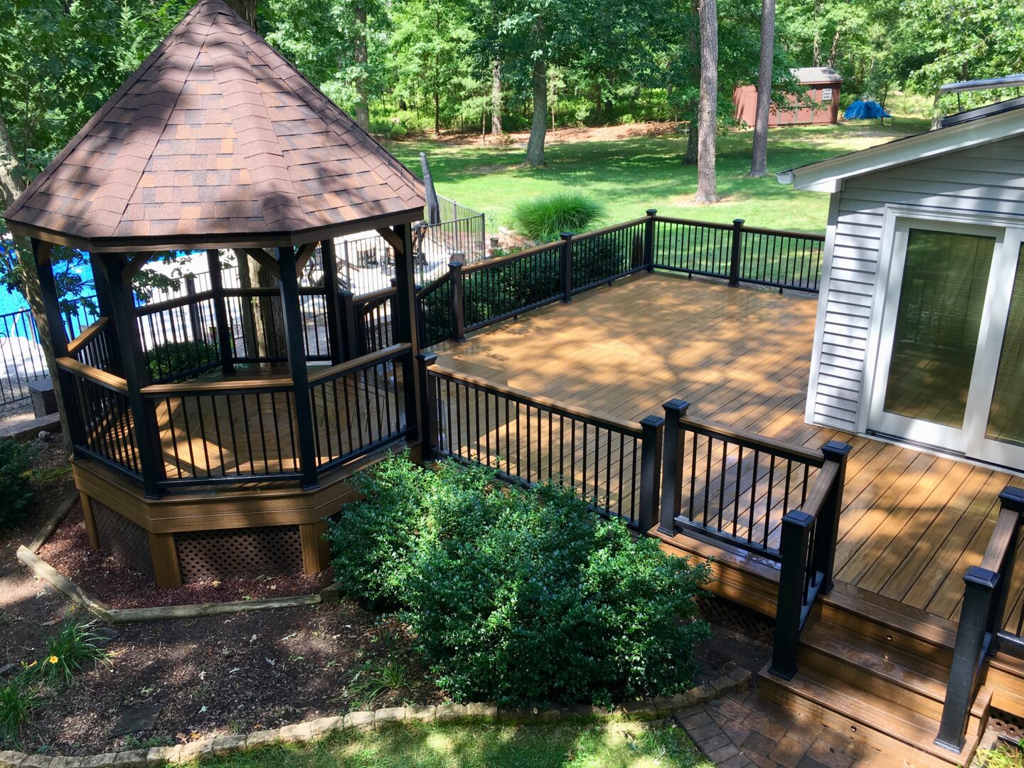 A gazebo with benches and a deck in the background.